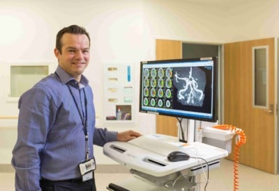 Stroke doctor with a x-ray image of a brain behind him
