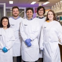 A group of five researchers standing in a lab