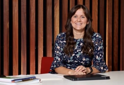 Woman smiling at camera with a laptop on desk