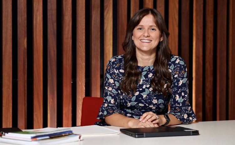 Woman smiling at camera with a laptop on desk