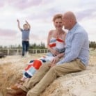 Husband and wife sitting on a beach with son playing in the background