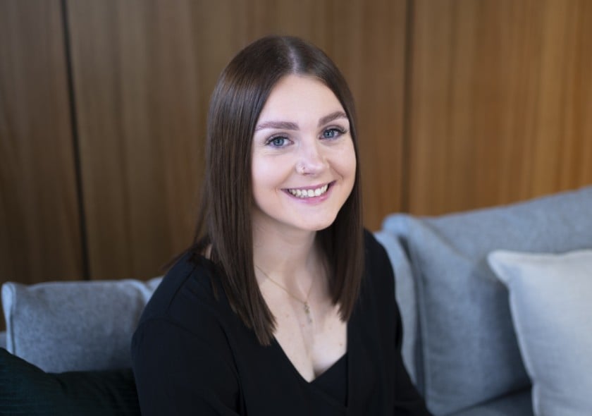A young woman seated on a couch smiling at the camera