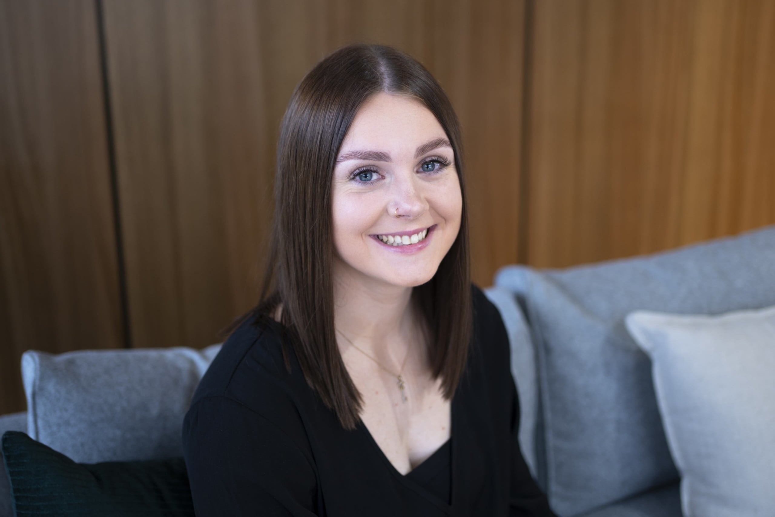 A young woman seated on a couch smiling at the camera