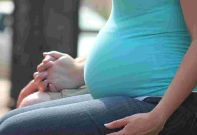A picture of a pregnant person sitting, with focus on her belly. Low levels of Omega-3 proven to be a key risk factor for premature births.