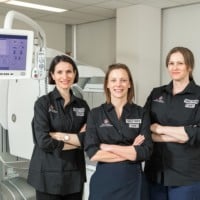 Three women standing with their arms crossed in a hospital