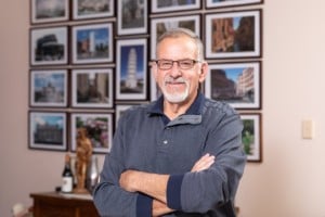 Atrial Fibrillation survivor Danny smiles at the camera in front of photo frames.
