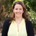 Registered Psychologist and Senior Research Fellow in late life mental health Monica Cations smiles at the camera in a yellow top and black cardigan