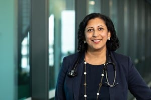 Kidney researcher A/Prof Shilpa Jesudason smiles at the camera in a hospital hallway. She has a stethoscope around her neck. 