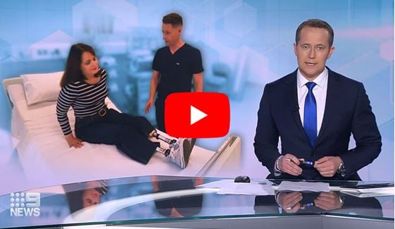 Caroline, who lost both her legs after contracting sepsis during childbirth, sitting on hospital bed talking to researcher Dr Mark Plummer.