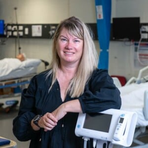 Professor Marion Eckert in hospital ward smiling at camera