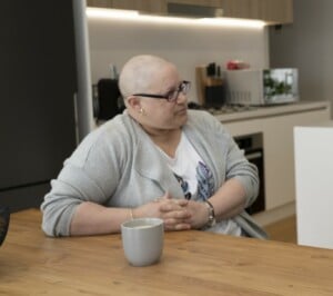 Cindy sitting at dining table with fingers interlocking