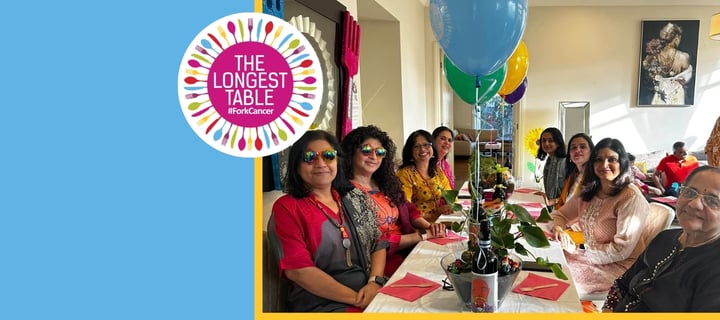 Family members sitting around a Longest Table with coloured helium balloons